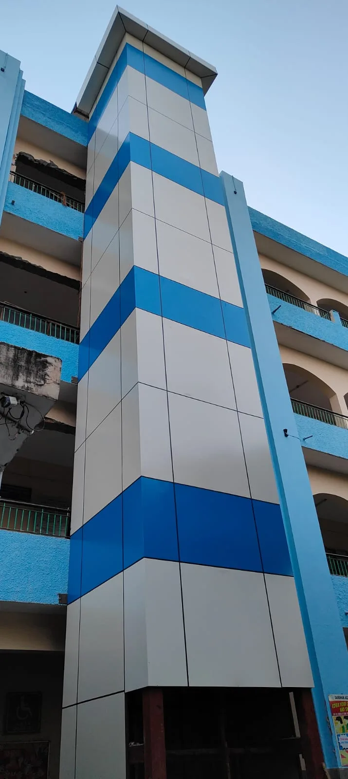 Blue and white ACP-clad elevator shaft on an institutional building