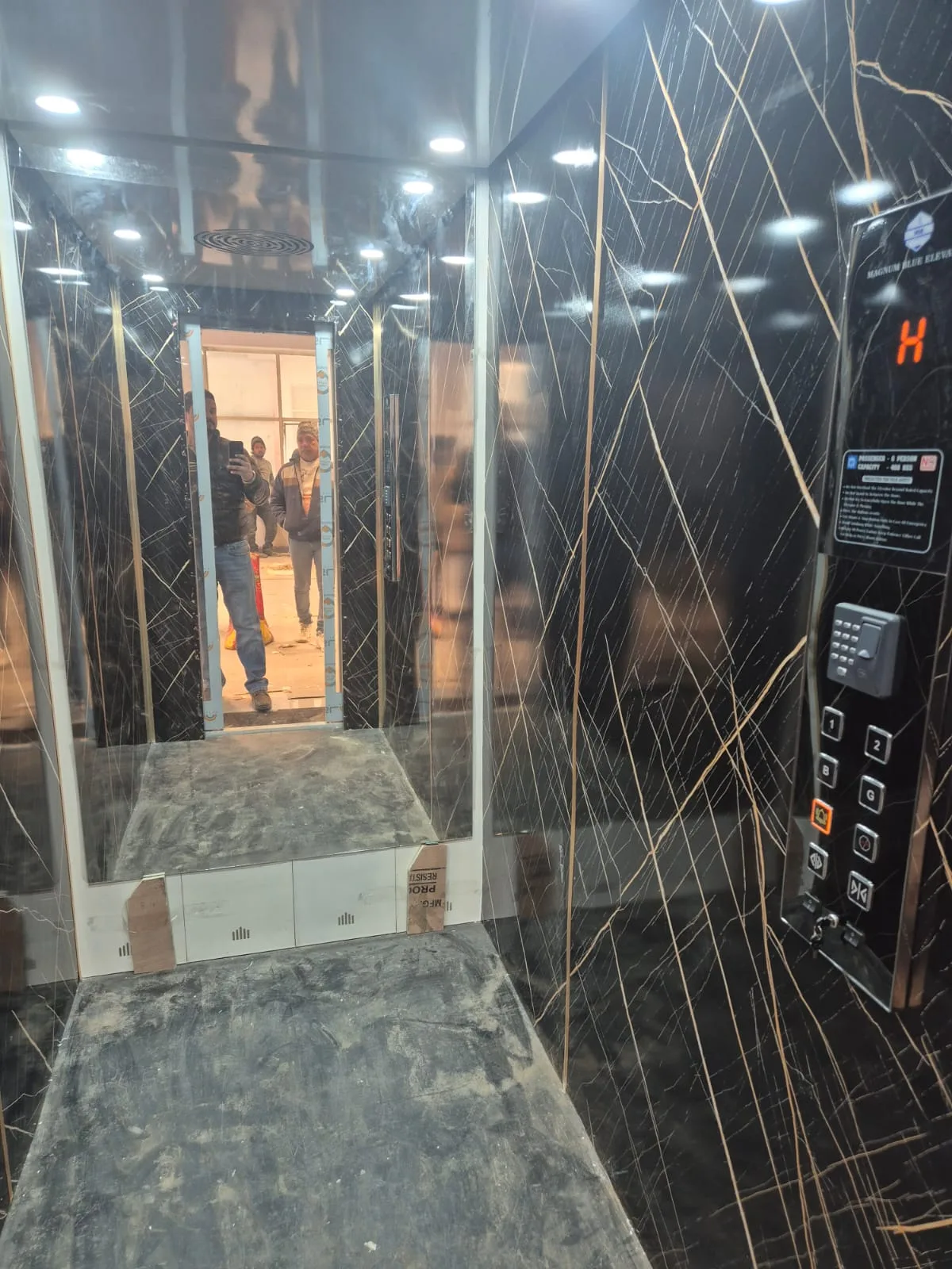 Marble-clad elevator cabin interior with MB Elevator branded control panel